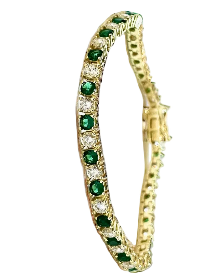 Gold bracelet with green gemstones on a white surface