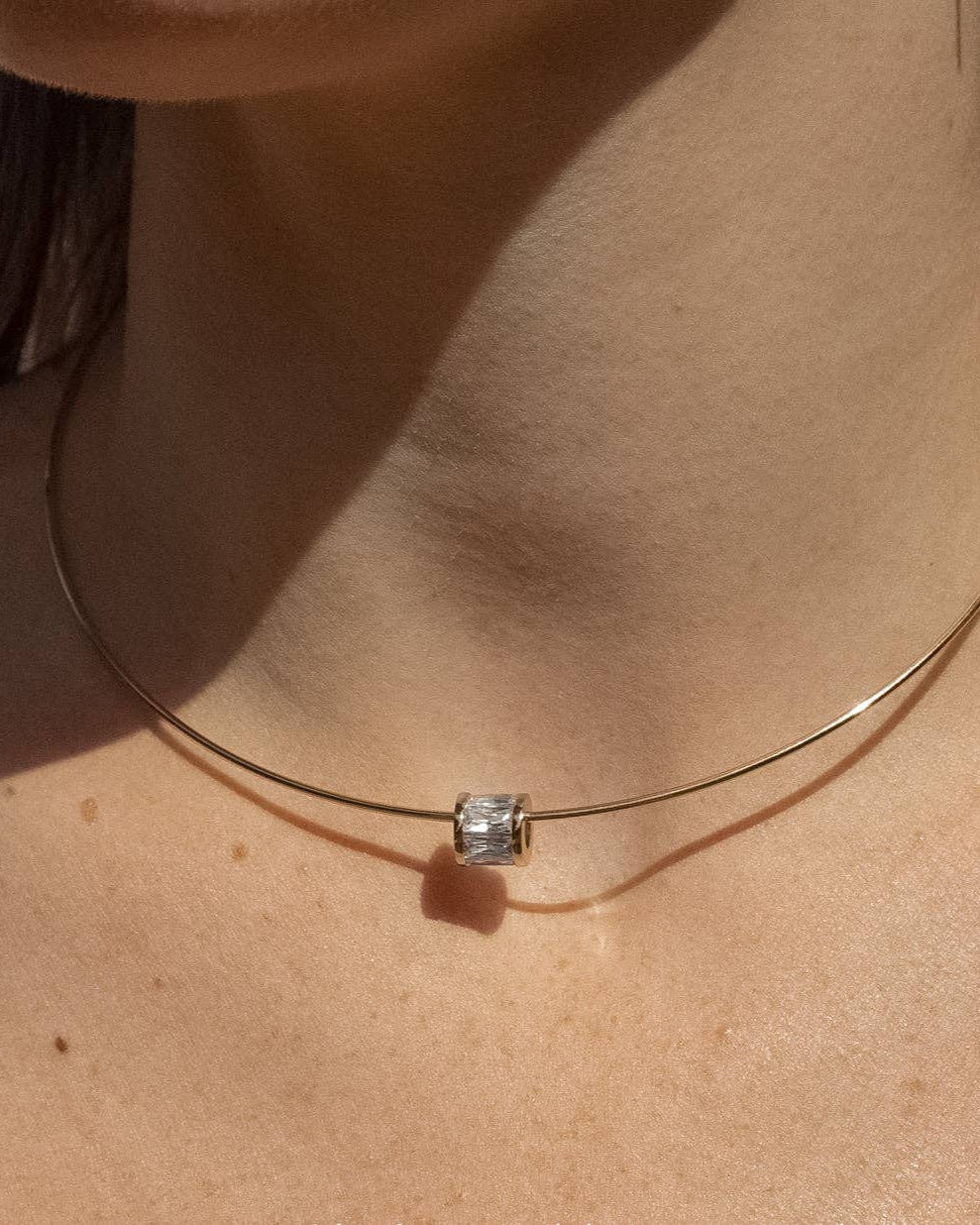 Necklace with a square pendant on a person's neck