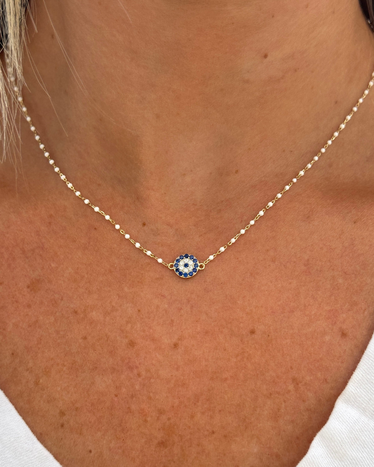 Necklace with a blue eye pendant worn by a person