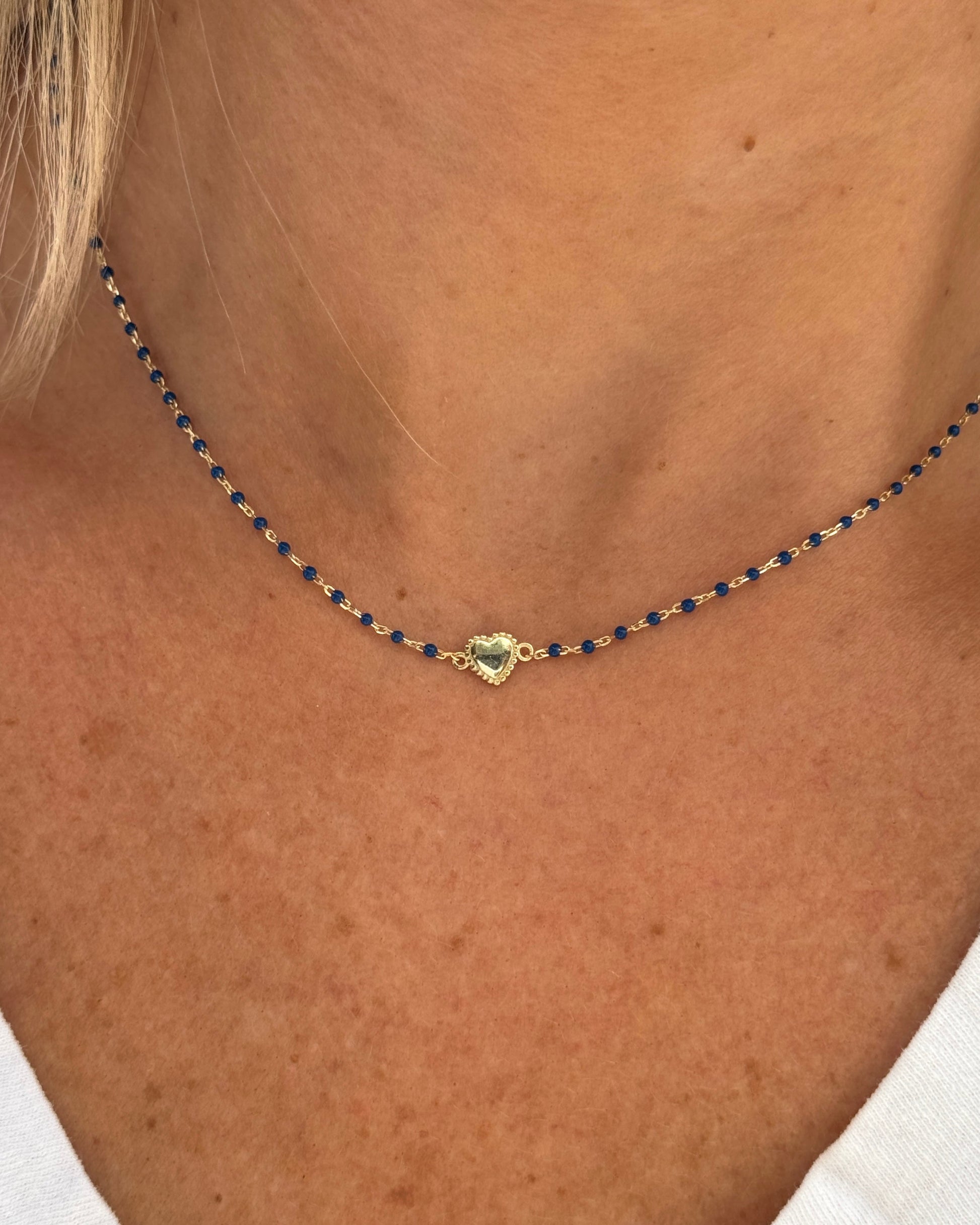 Necklace with a heart-shaped pendant on a person wearing a white top.