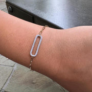 The DIDI Gold Diamond Bracelet by AIRA, featuring a large oval diamond-encrusted link on a 14kt yellow gold chain, is worn on a person's wrist.