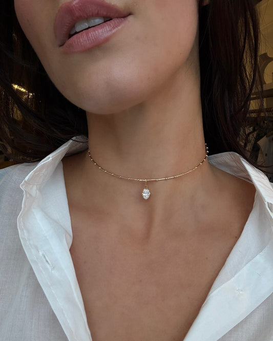 Close-up of a person wearing a delicate gold necklace with a small pendant.