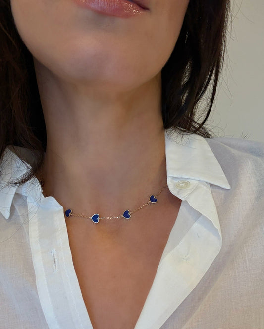 Necklace with heart-shaped pendants worn by a person in a white shirt.
