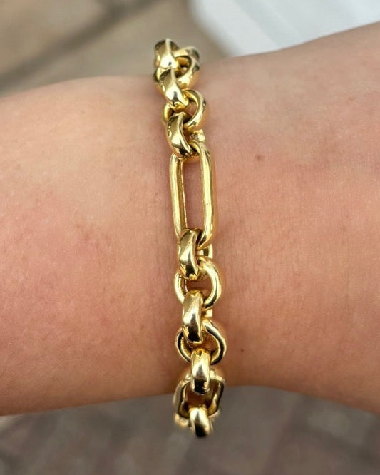 Gold chain bracelet on a wrist with a blurred background