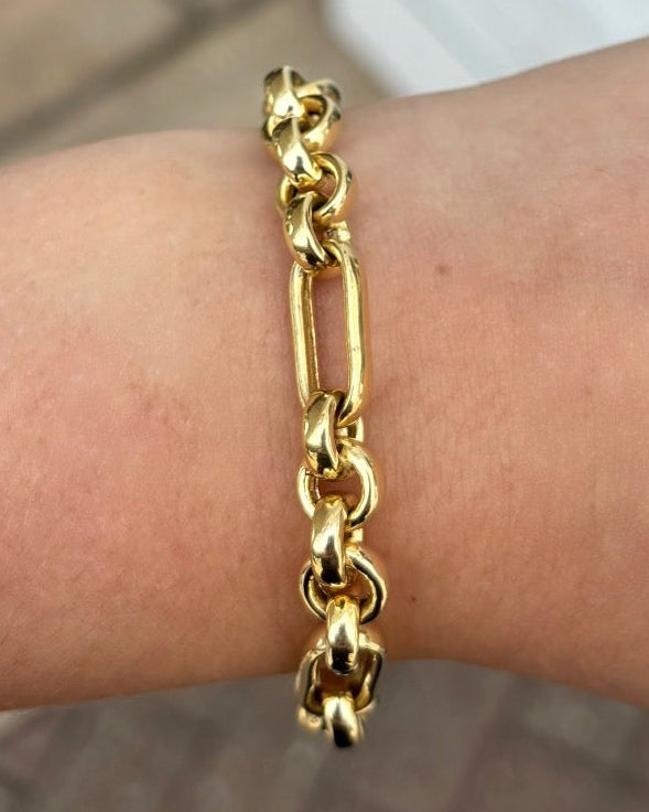 Gold chain bracelet on a wrist with a blurred background