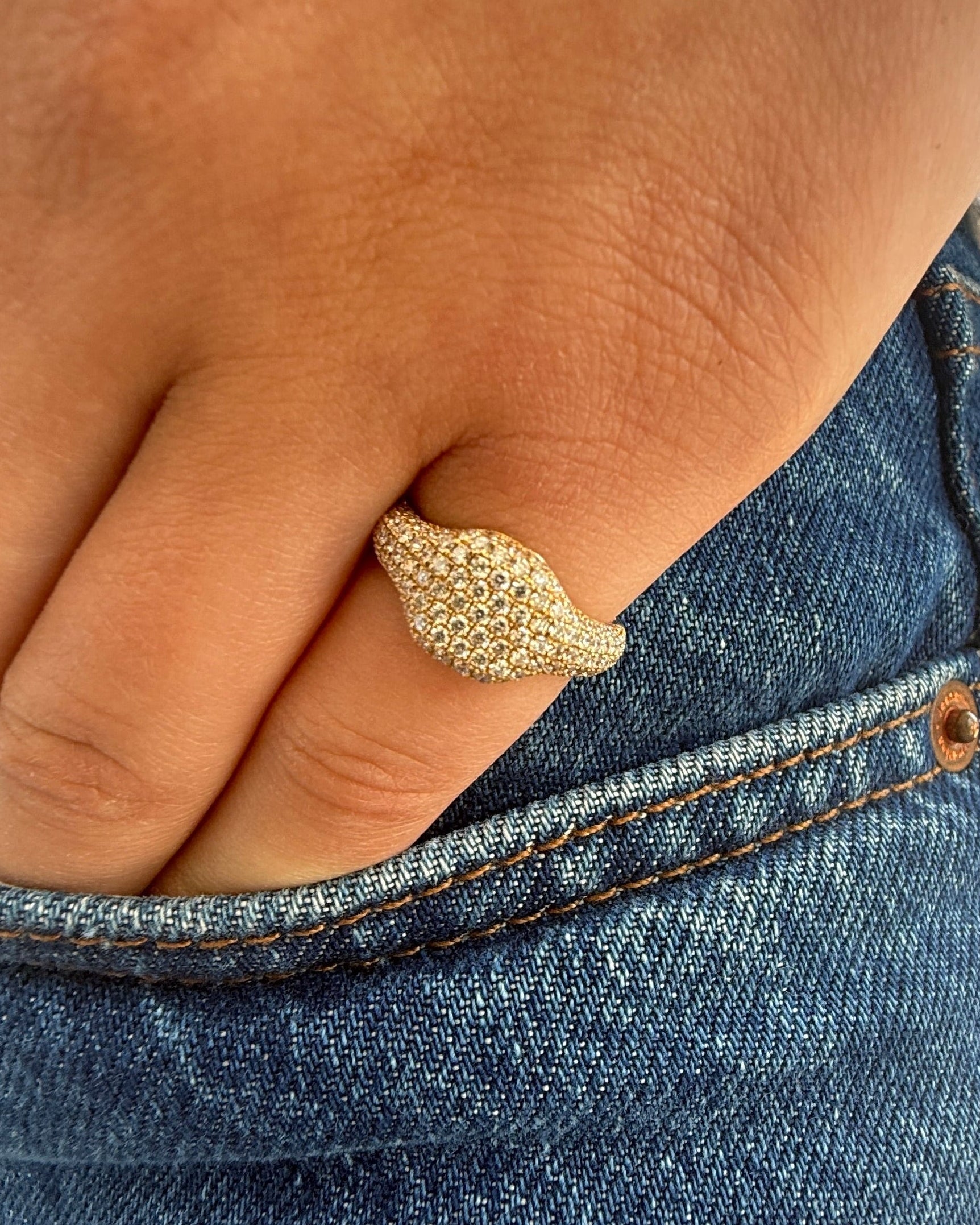 Gold ring on a finger with a denim background