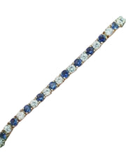 Bracelet with blue and clear gemstones on a hand against a dark background