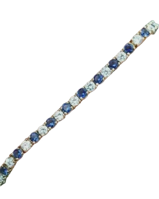 Bracelet with blue and clear gemstones on a hand against a dark background