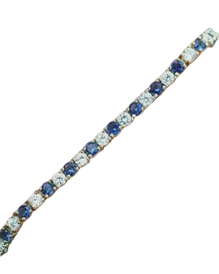 Bracelet with blue and clear gemstones on a hand against a dark background
