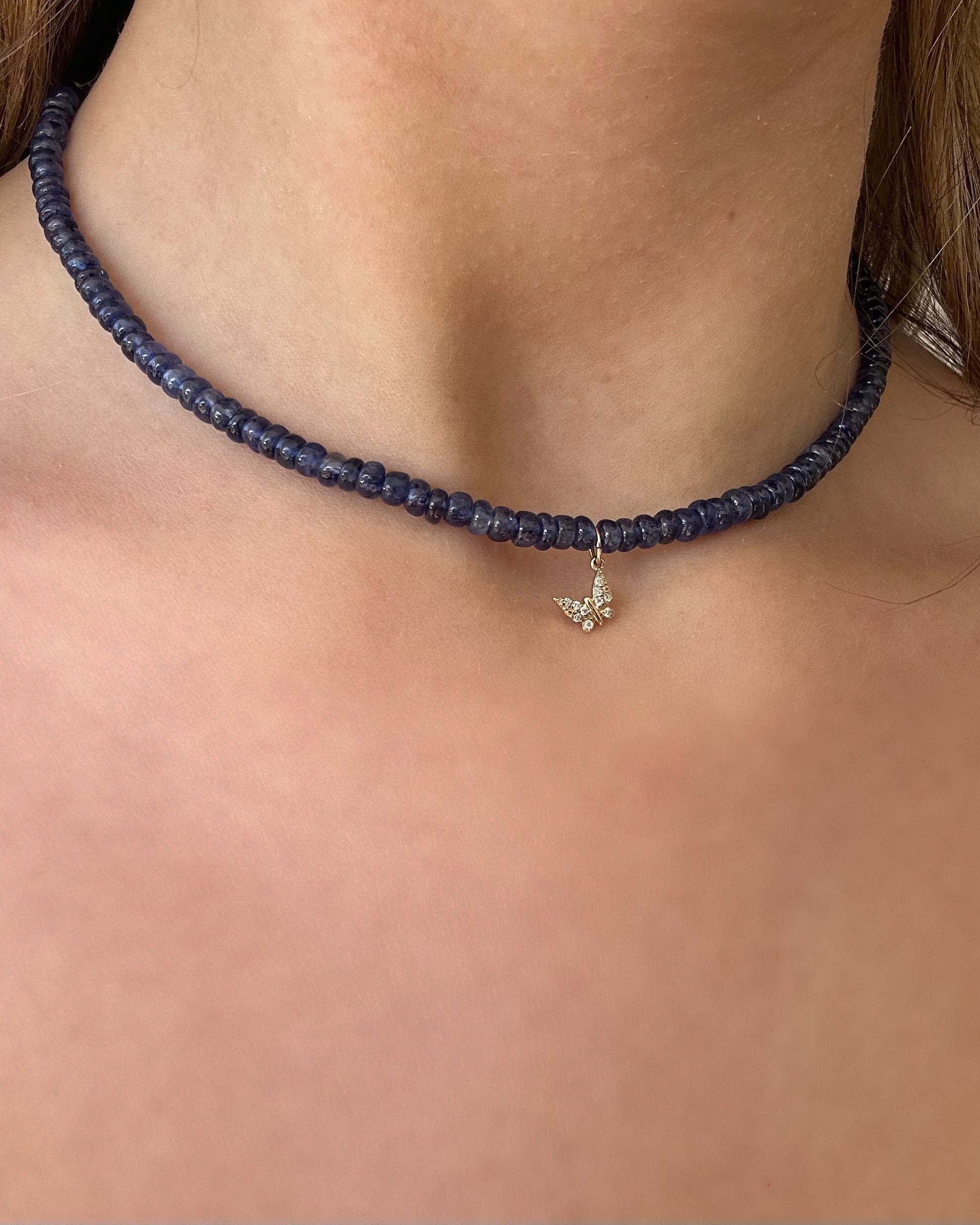 Navy blue beaded necklace with a butterfly pendant on a person's neck