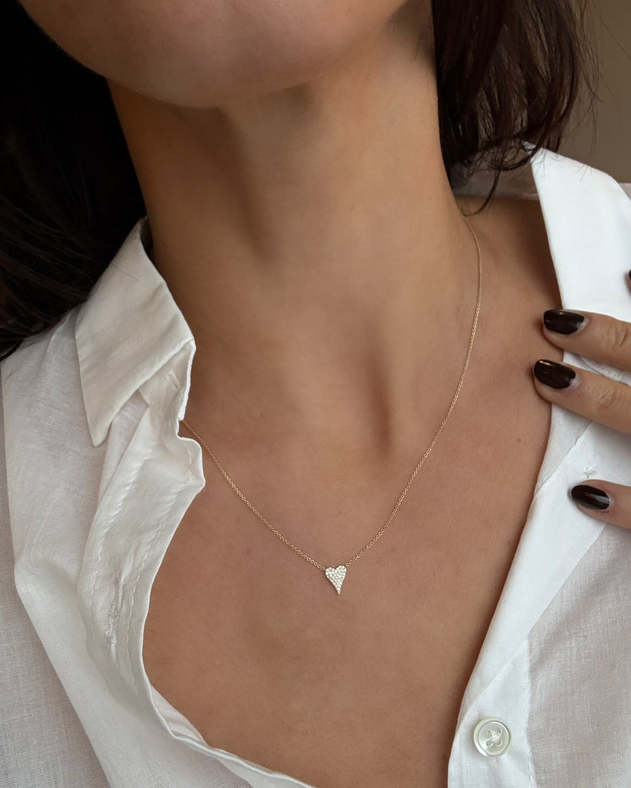 Heart-shaped necklace worn by a person with a white shirt
