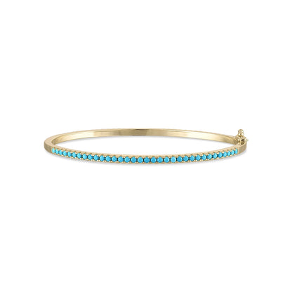 SKN's MARNI Gold Diamond Turquoise Bangle is crafted from yellow gold vermeil and adorned with a row of small turquoise stones along the top, complete with a clasp closure.