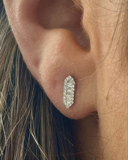 Close-up of an ear wearing a diamond earring with blonde hair.